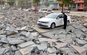A security personnel looks inside a car parked among debris at a site demolished as part of a street broadening project in Taiyuan